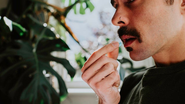 Close-up of a man taking a blue pill 