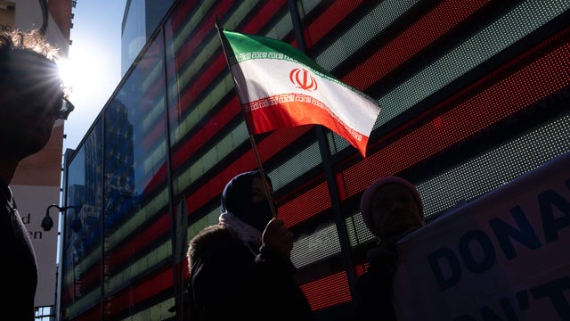 A demonstrator holds an Iranian national flag during a protest against war in Iran, in Times Square in New York, US, on Saturday, Feb. 28, 2026. 