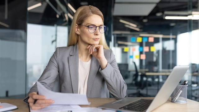 Worried female entrepreneur leaning on elbow and looking at computer screen 