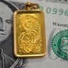 A closeup view of American dollars USD money banknote and Lady Fortuna motif on a gold bar pendant, 24K Gold Bar, pure fine gold 999.9, for investment or savings 