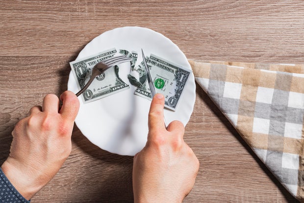 Hands of unknown person cutting banknote 