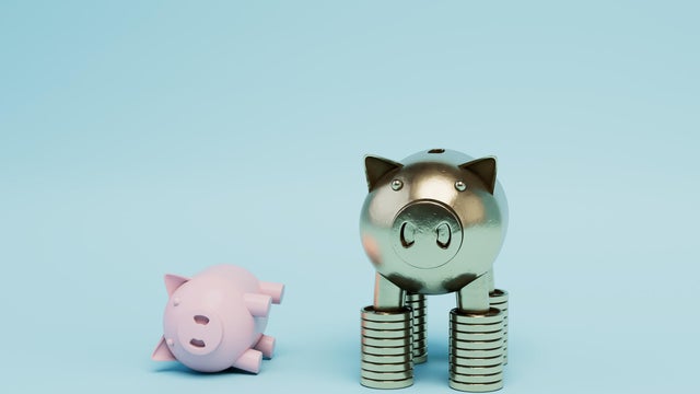 gold piggy bank standing on stacks of gold dollar coins with a piggy bank lying next to it. 3D render 