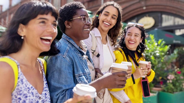 Four female friends holding cups of coffee 