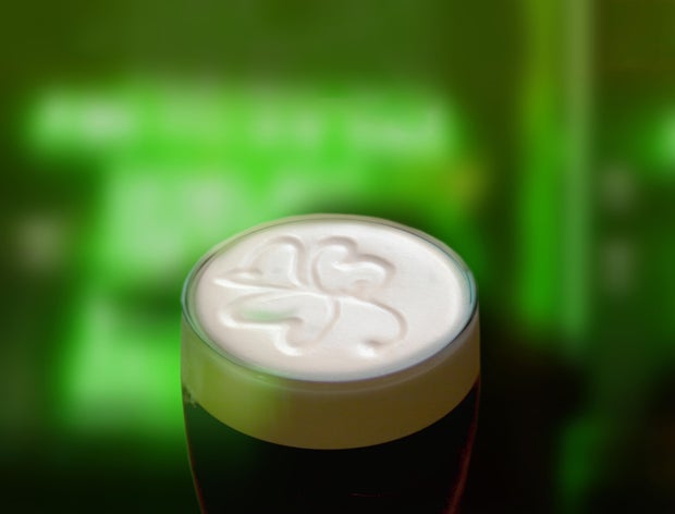 Famous black Irish stout with a frothy shamrock. Green St Patricks day background 