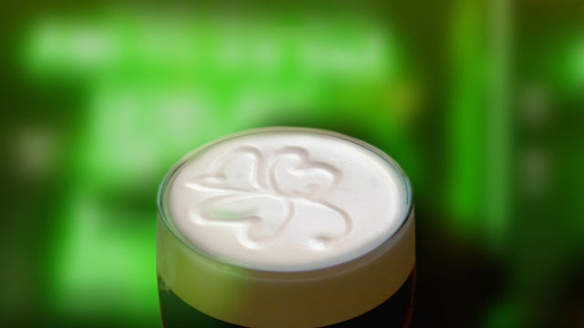 Famous black Irish stout with a frothy shamrock. Green St Patricks day background 