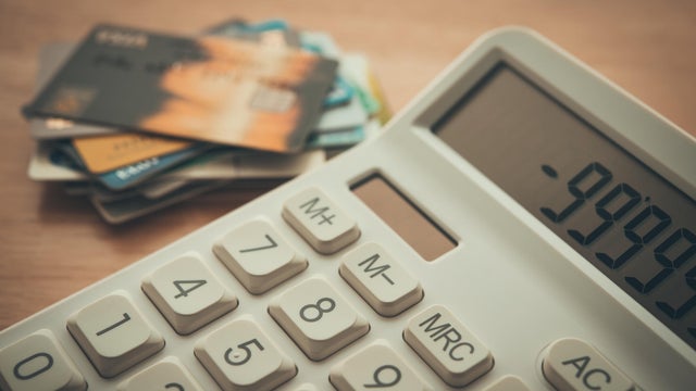 White calculator shows minus delinquent and many credit cards on wooden table background. 