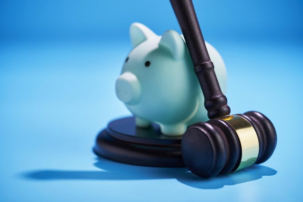 gavel hammer leaning on the piggy bank. 