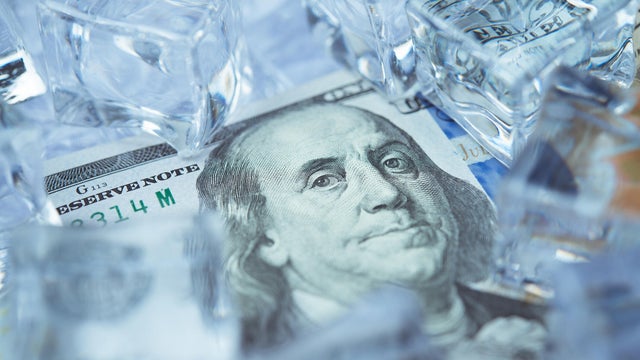 Close up frozen one hundred US dollar bill banknote with ice cubes. 