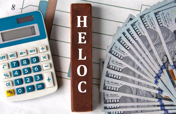 HELOC - word on brown wooden blocks on the background of a graph and banknotes 