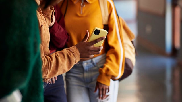 Midsection of friends sharing smart phone 