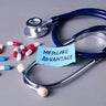 Medicare Advantage Concept with Stethoscope, Note, and Capsules on Gray Background 