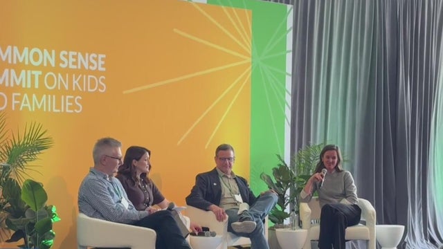 four people sitting on a stage during a conference 