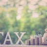 Understanding the Impact of Taxes on Savings and Investments: The word TAX displayed alongside stacks of coins with several icons on top e.g. a piggy bank, a sprouting plant, a car and a family house. 