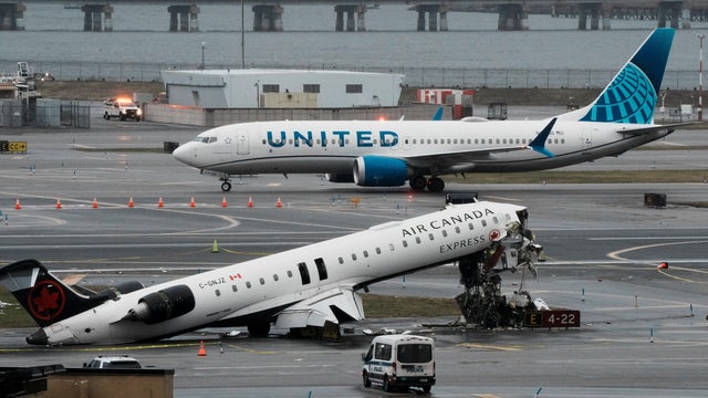 A United Airlines aircraft taxis next to the wreckage of an Air Canada Express jet that collided with a fire truck at New York's LaGuardia Airport in Queens, New York, March 23, 2026. 