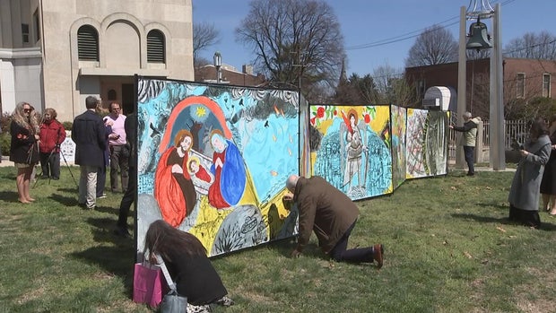 People kneel to add to the painting outside the church 