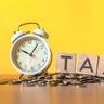 Tax text written on wooden block with stacked coins 