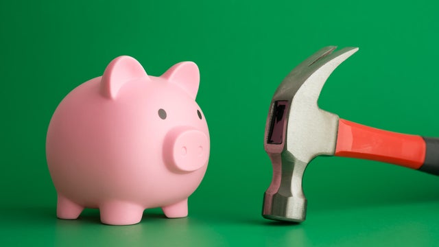 Pink piggy bank face to face hammer on green background. 
