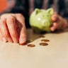 senior women Hand collecting coins on a table with a piggy bank in the background 