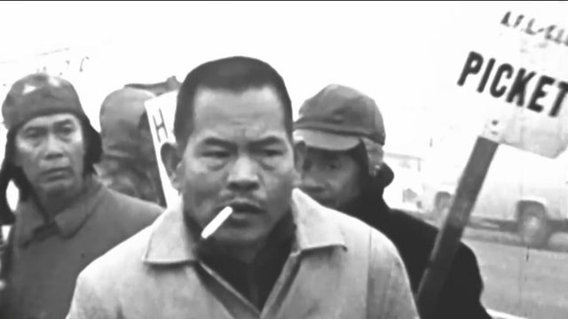 A man leading a strike with a sign that reads picket behind him 