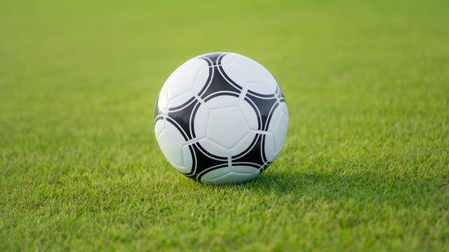 A plain black and white soccer ball on green grass. 