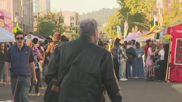 a crowd of people on a city street that is lined with vendors 