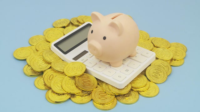 Piggy bank and calculator on heap of gold coins 