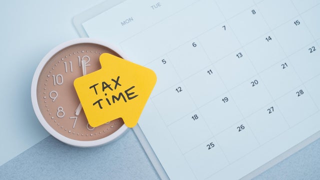 Tax time concept. Reminder sticker on clock and calendar background 