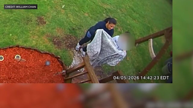 Woman and child hold blanket in yard 