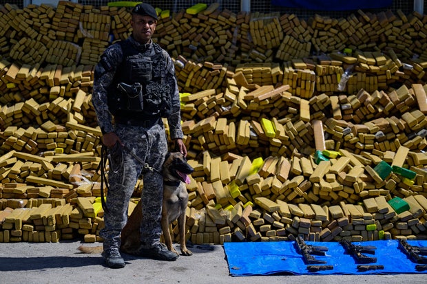 A police dog that took part in an operation in which 48 tons of marijuana were seized poses in front of packages containing the drug and weapons in Rio de Janeiro on April 8, 2026. 