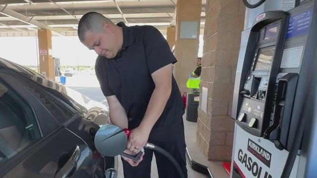 A man holding a gas pump filling up his car 