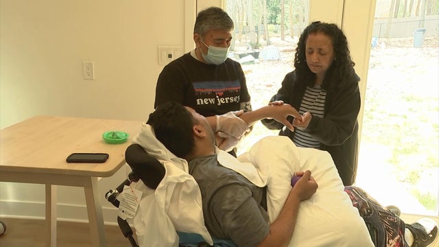 A health care worker and Manjina Patel care for Kishan Patel at home 