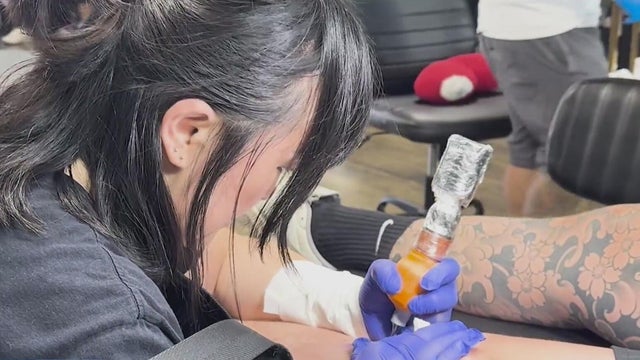 An artist tattooing a person's leg 