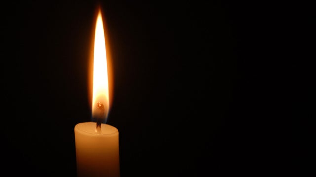 Single candle flame on horizontal black background 