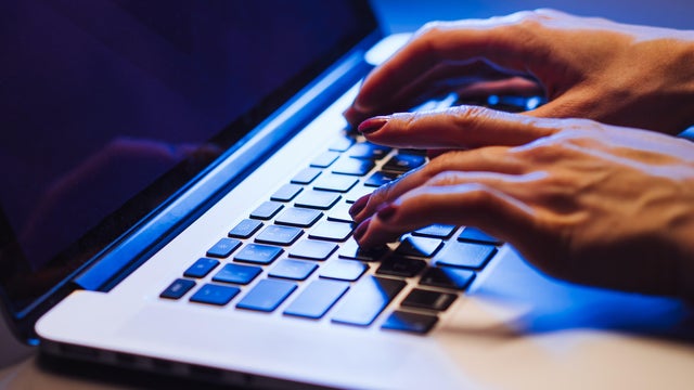 Woman Typing on a Laptop in a Cozy Ambient Setting 