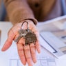 Person holding new house keys and home plans 