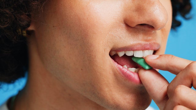 Chewing gum, dental and closeup of person in studio for fresh breath, oral hygiene or candy. Cleaning, mint sweets or bubblegum with snack and mouth on blue background for teeth care and eating 