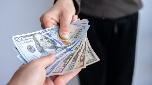 Cropped shot view of someone giving America dollar banknotes to other person. 