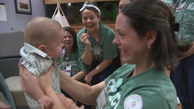A nurse smiles at Baby Alton as she holds him 