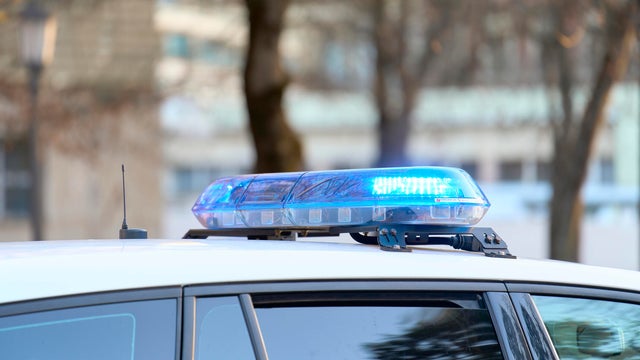 a close-up view of a police vehicle with blue lights patrolling near a public park with the windows and doors closed 