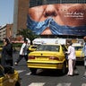 People walk past an anti-U.S. billboard depicting U.S. President Donald Trump and the Strait of Hormuz, in Tehran 