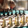 A woman starts a chess game with the first move of a pawn 