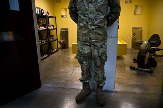 In this photo reviewed by U.S. military officials, a U.S. soldier stands between two cells, one used as a library and the other a gym, inside the Camp VI detention facility at the Guantanamo Bay U.S. naval base in Cuba on June 6, 2018. 