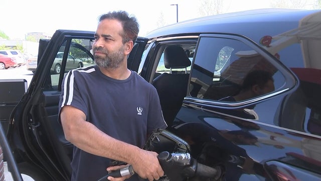 A man looks at the screen as he fills up his gas tank 