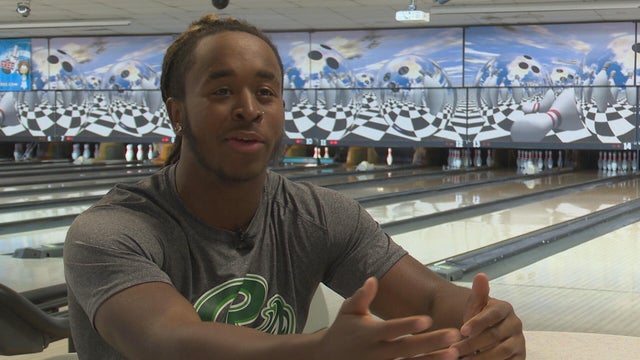 Troy Carey talks to a reporter at a bowling alley 