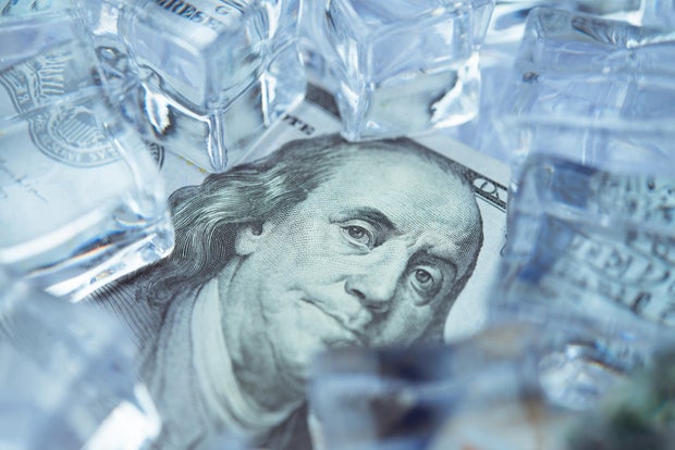 Close up frozen one hundred US dollar bill banknote with ice cubes. 