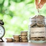 Hand putting Coins in glass jar with retro alarm clock 