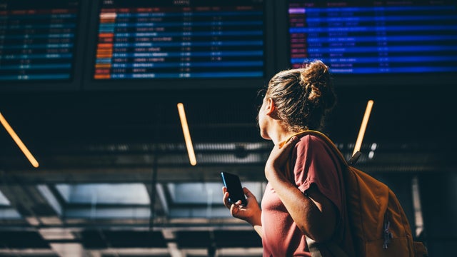 Woman checks airline schedule at airport. 