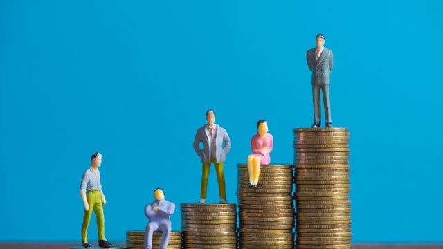 Figure miniature businessman or small people investor and office worker secretary standing on coin stack, for money and financial business success concept. 