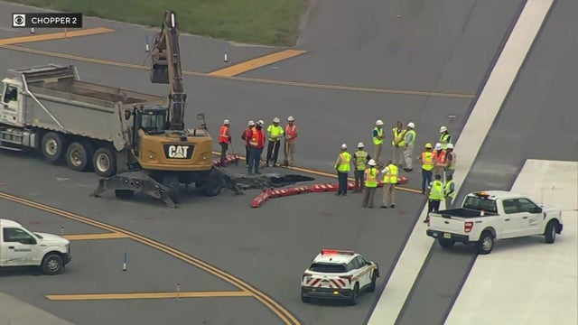 Crews stand around a sinkhole near a LaGuardia Airport runway 