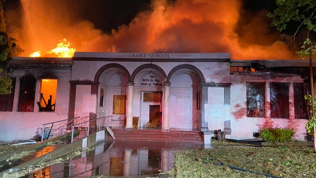 a building with flames seen rising behind it 
